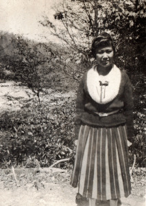 Maya Sudo Album: Maya standing and facing camera; in striped skirt. 009a